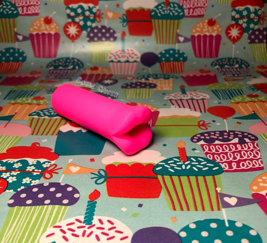 Slanted front view of Kyst Lips in hot pink from Calexotics on top of a cupcake background.