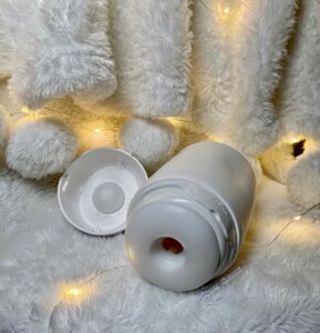Tenga Puffy Sugar White on a white fuzzy material, the end cap is propped on the side. 
