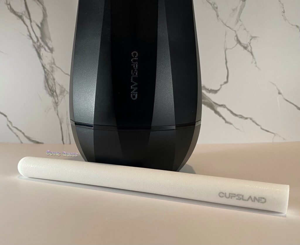 Black case of the Cupsland Twirl 1.0 The brand name can be seen on the case, with the white drying rod placed in front of it. The word Cupsland can be seen stamped on the drying rod.
