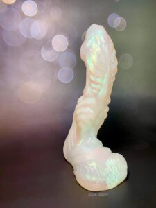Underside of the Mothman dildo's shaft, the dildo is standing upright. Black bokeh light background.