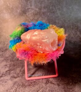 The Falkor Micro Stroker sitting in a miniature fuzzy, colorful chair. 