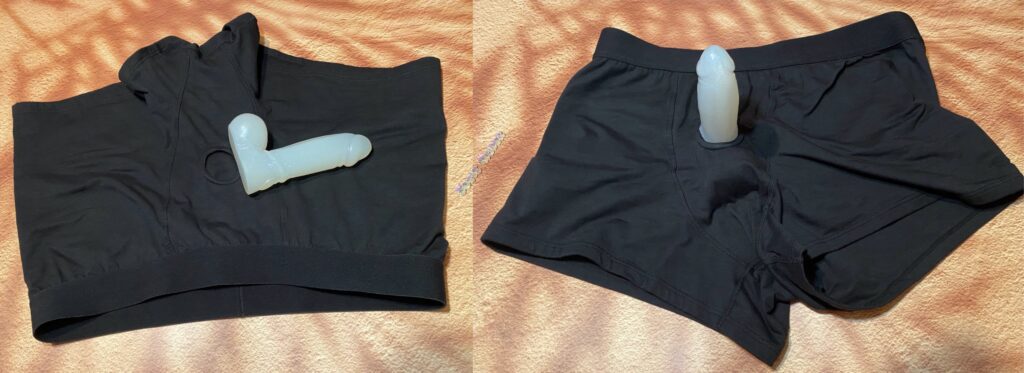 Two pictures side by side of the Black SnugHer boxer harness from Crassie with a white, glittery dildo in the o ring on one picture, and laying on top of the harness in the other picture. The dildo has balls. 