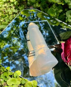 Elwyn posed facing away from the viewer, so the flat base can be seen. The floral ring and Squidly co logo can be seen well from this angle. Part of a red flower is visible on the right. 