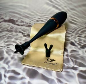 The tongue flicker attachment on the Orgasm Monster Pro sitting on top of the gold bag, with the bunny ear attachment sitting below. 