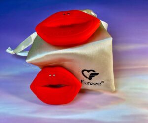 The backside of the lip shaped vibrating nipple clamps. They're on two different levels, one above one below, both against the gold drawstring pouch. 