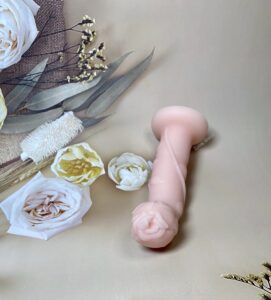 Rose bendable dildo laying with the head curved upward. The petals of the rose head are prominent 