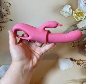 RiderGo, a pink rabbit-style vibrator being held by my hand.